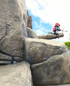 Styrofoam racoon statue sitting on log with concrete stone in foreground